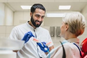 dentist showing patient teeth model to patient