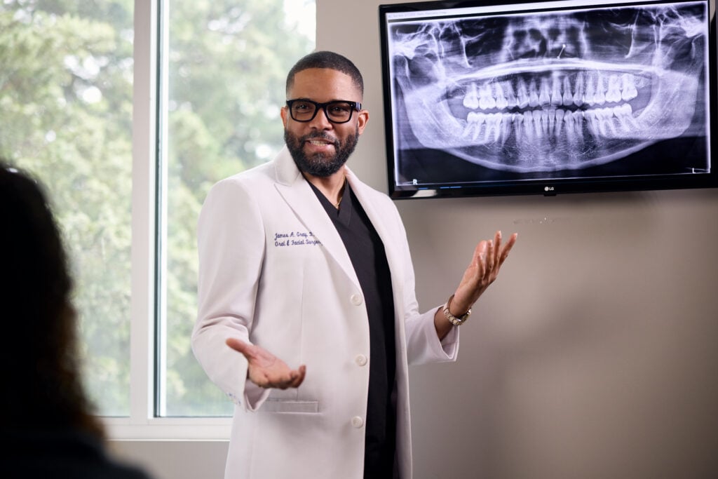 Dr. Gray explaining a panoramic dental X-ray displayed on a screen to a patient.